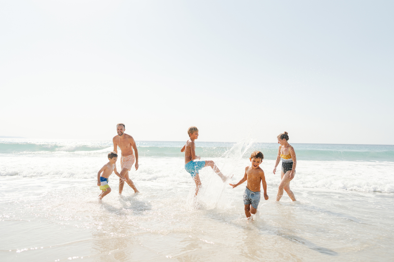 Photo of a family with three boys, spending quality time together on the beach